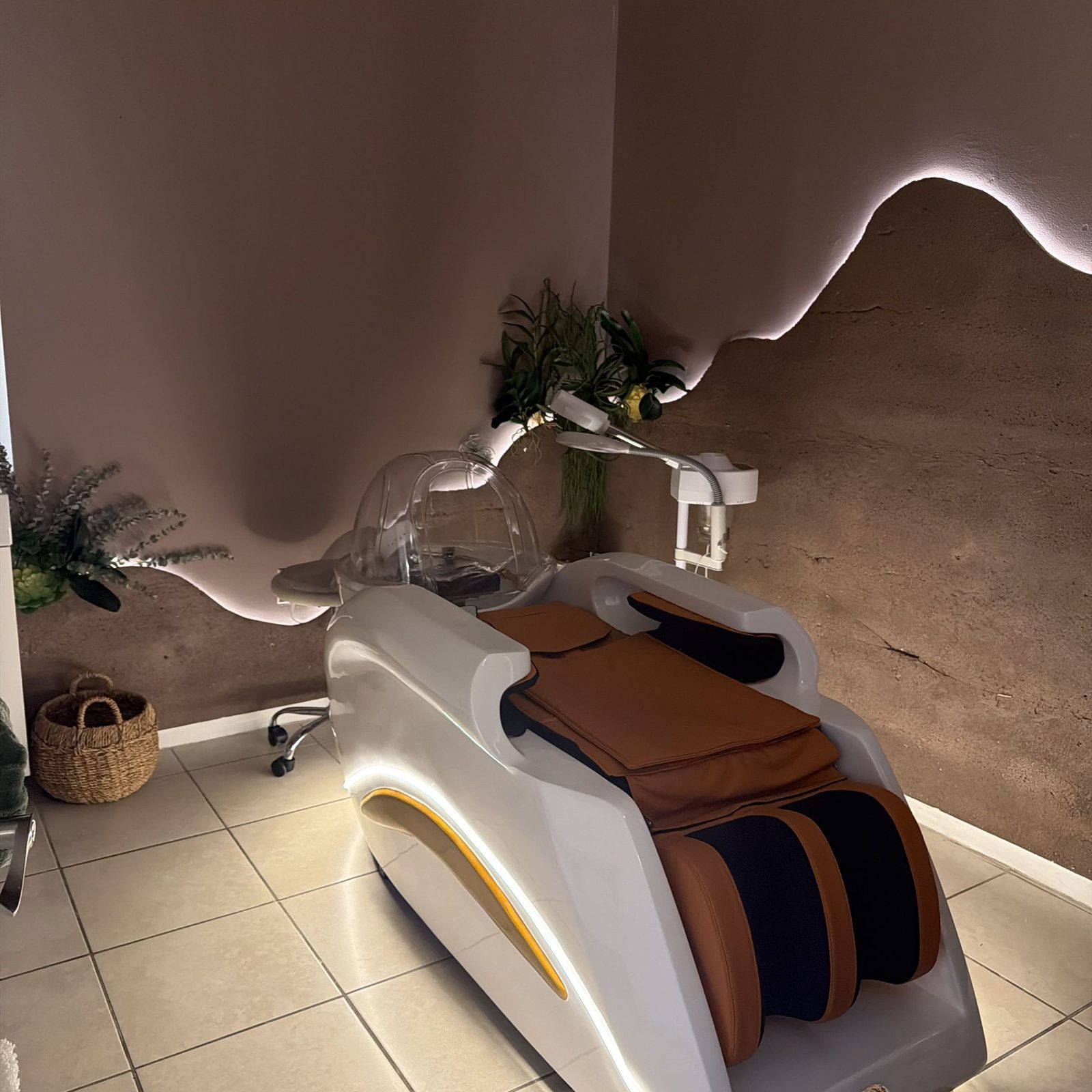 La sala de spa con la cama de masaje iluminada y plantas